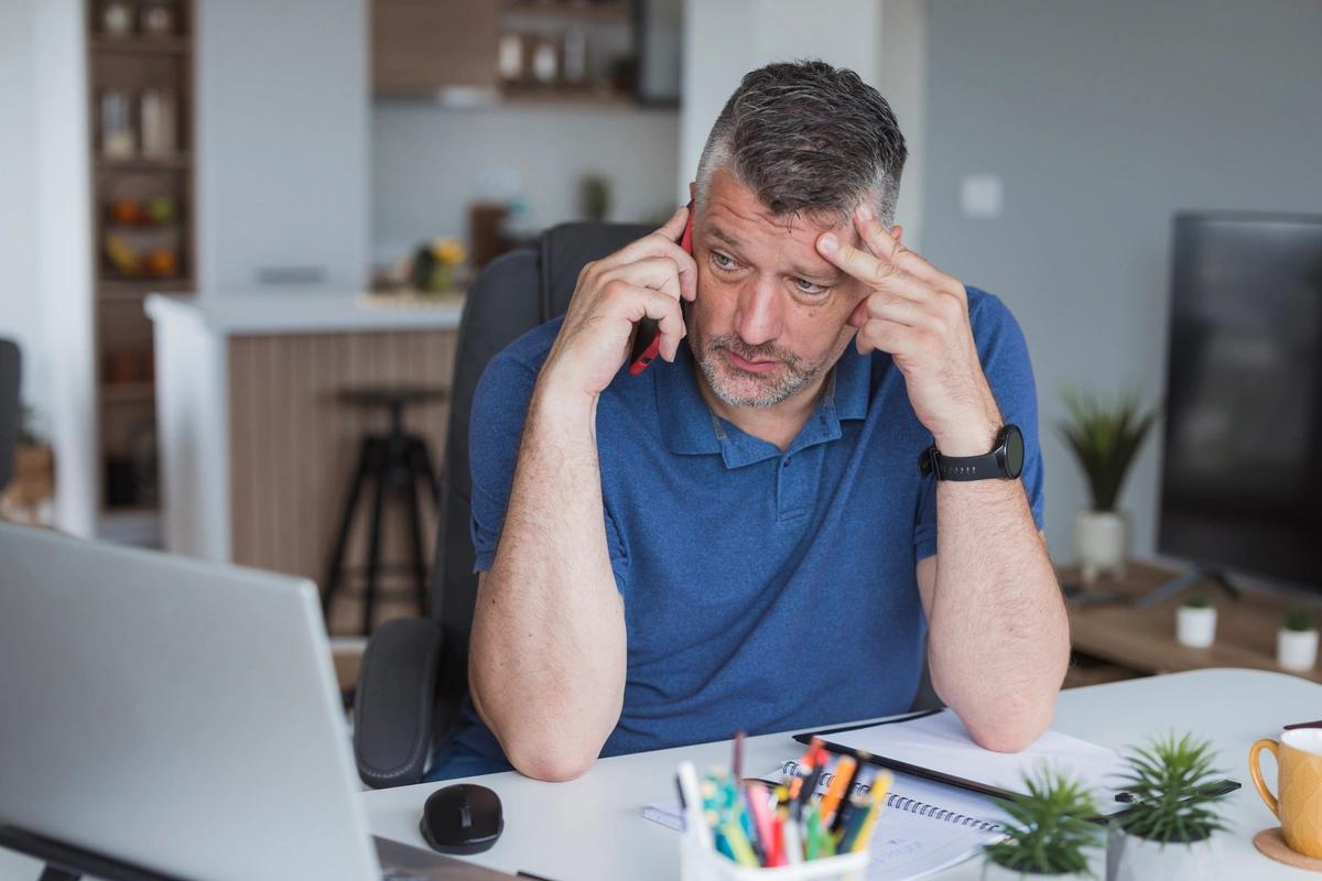 A worried-looking man trying to get hold of somebody on the phone