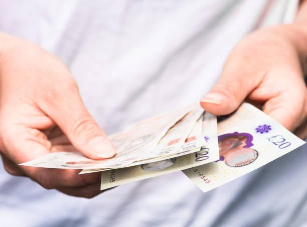 Image of a man counting £10 and £20 notes