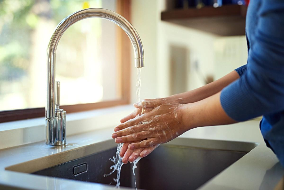 Someone washing their hands at the kitchen sink
