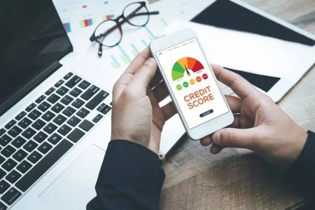 Image of someone looking at their credit score on their mobile phone in front oft their laptop. Millions of UK households missed a payment in 2025. Find out what a missed really means for your credit score.