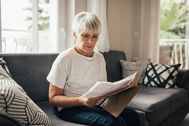 Image of a pensioner reading a bank statement. Millions of pensioners could be owed money after HMRC tax error. Pension credit.