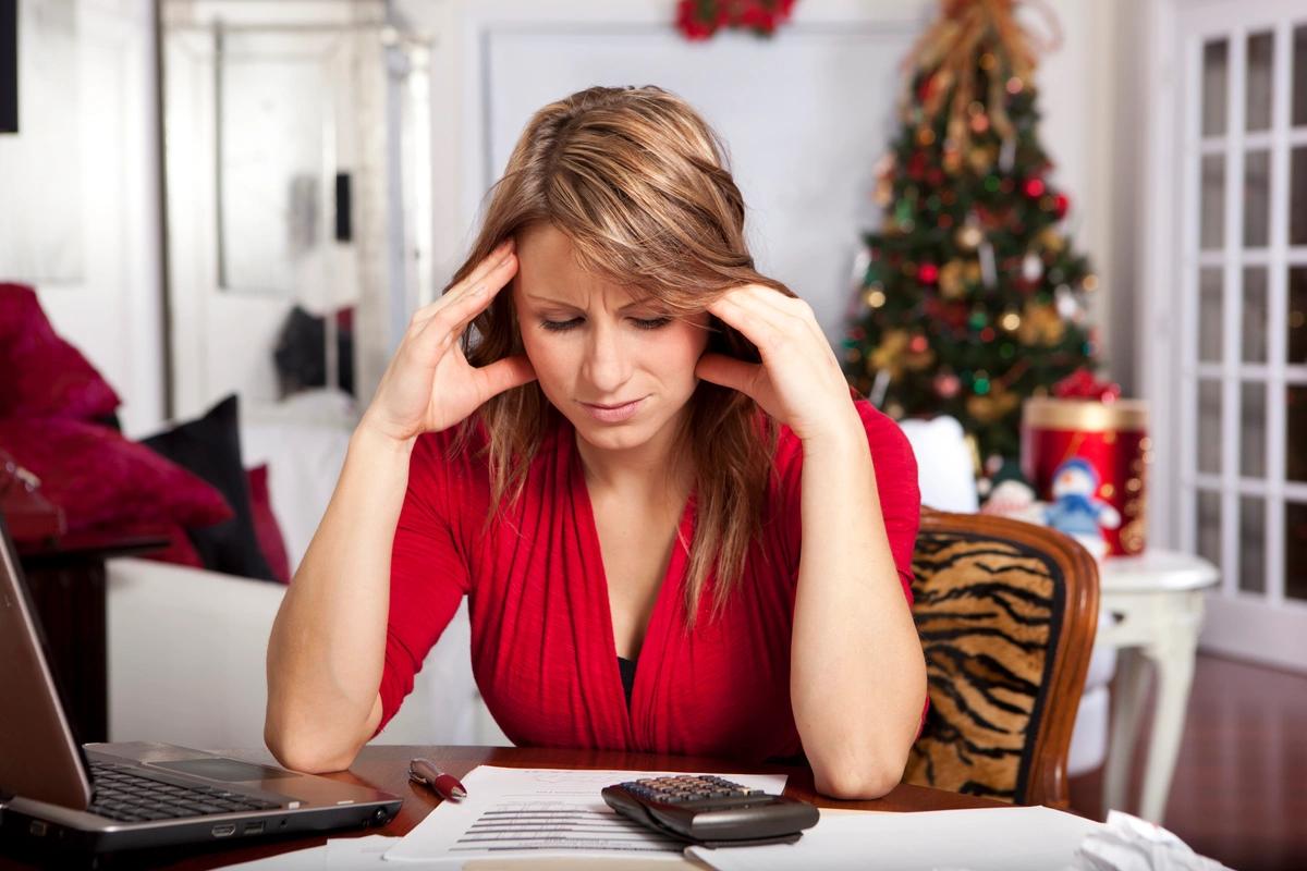 A worried woman goes through her finances in a room decorated for Christmas