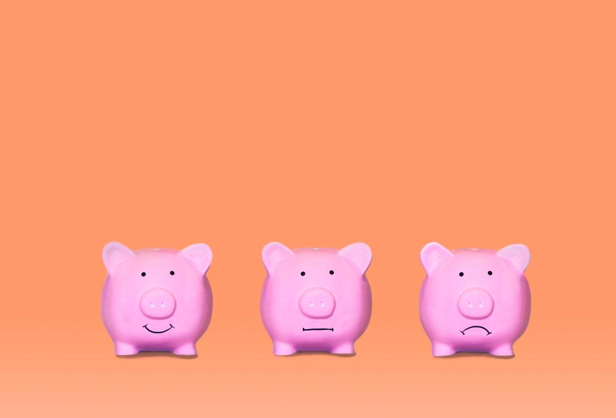 Three piggy banks - one smiling, one with a neutral expression and one looking sad