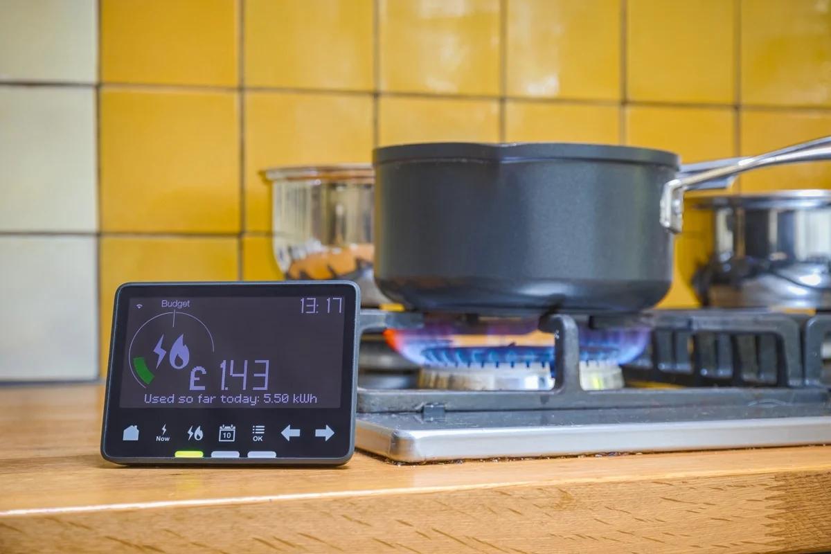 A smart meter display in front of a pan on a gas hob