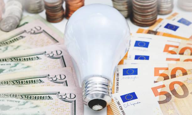 Image of a lightbulb surrounded by dollars and euros. Why Brits pay more for energy than most of Europe