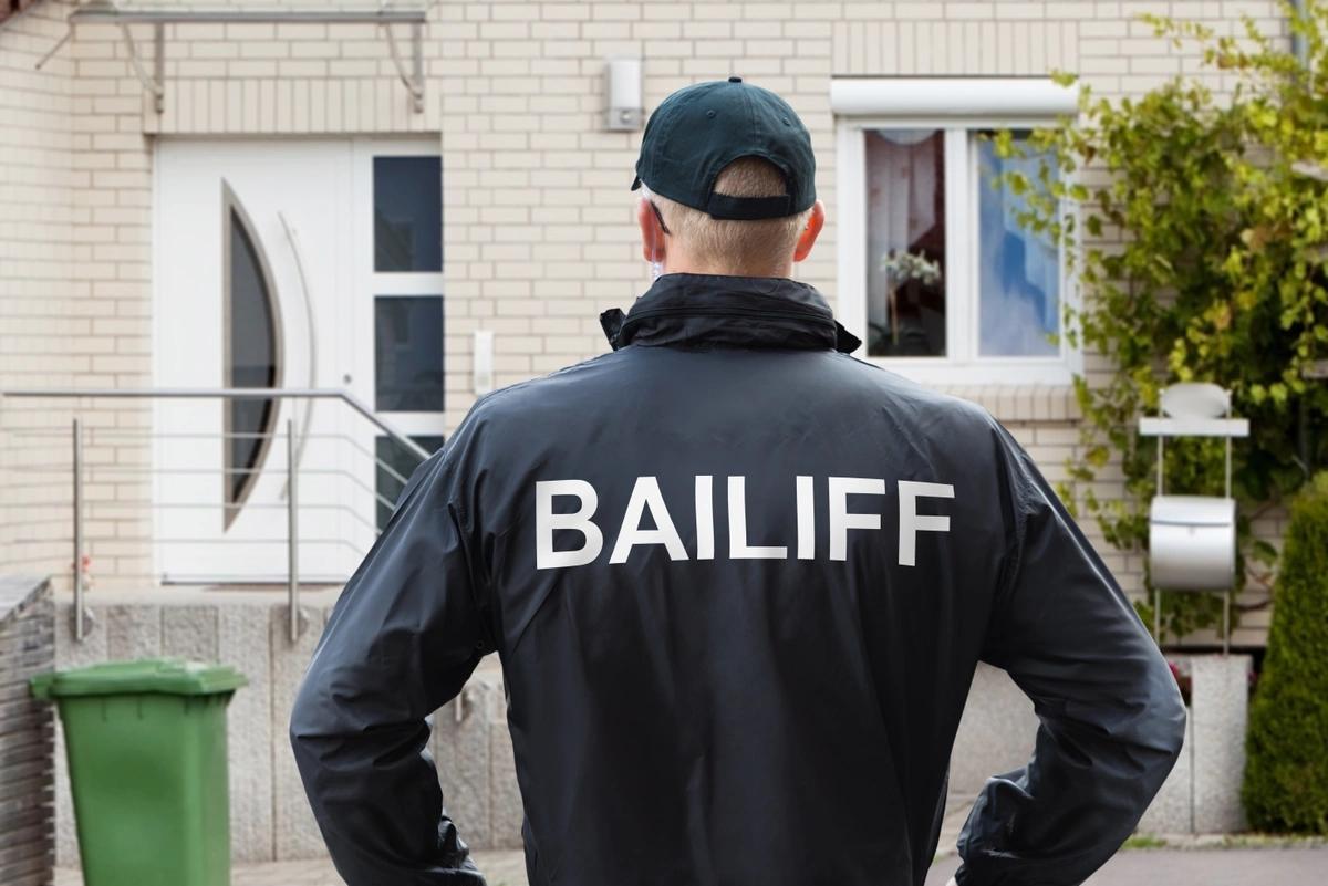 Bailiff standing at entrance to home