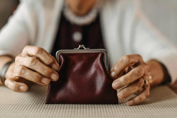 Image of a pensioner holding a coin purse in the foreground. Pensioners urged to claim pension credit to get backdated cost of living £299 payment