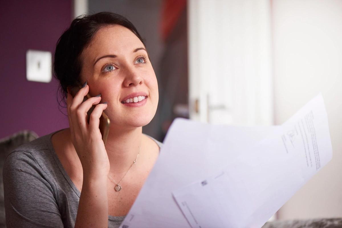 Woman on phone holding paperwork