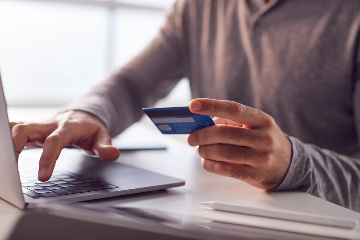 Close-up of a man paying for something on a laptop using a credit card