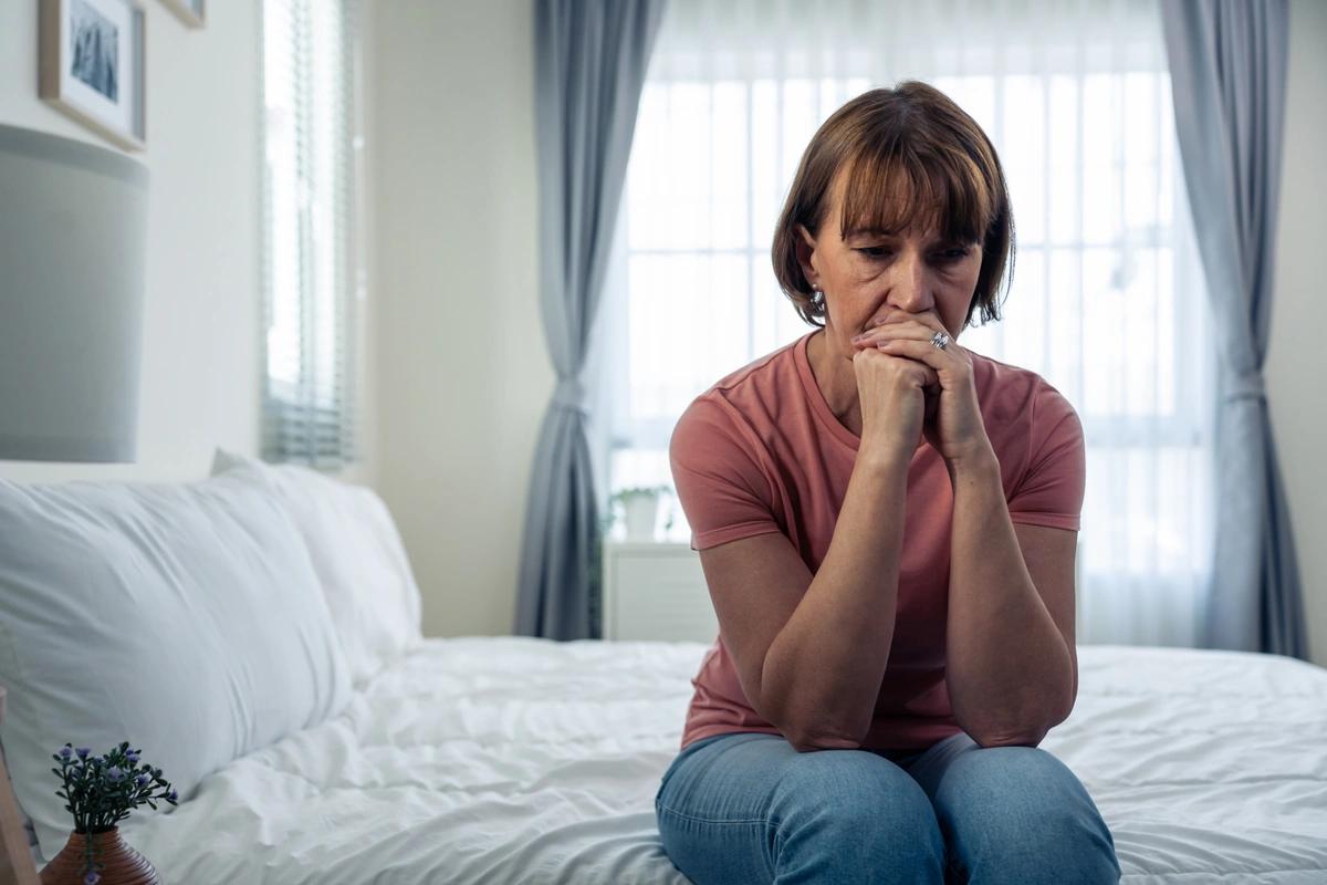 A worried-looking older woman sitting on her bed after receiving a no-fault eviction notice