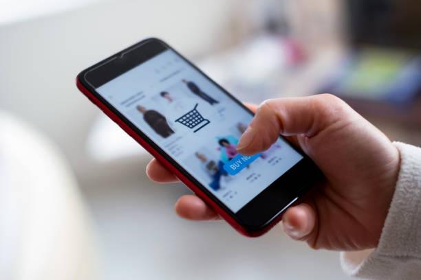 Image of a man holding a mobile phone doing online clothes shopping