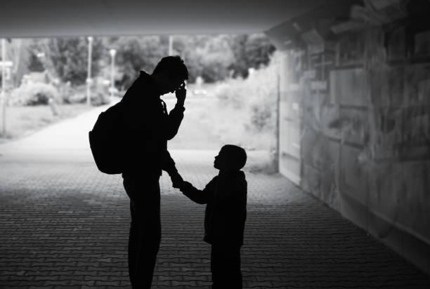 black and white image of a dad looking upset holding his son's hand