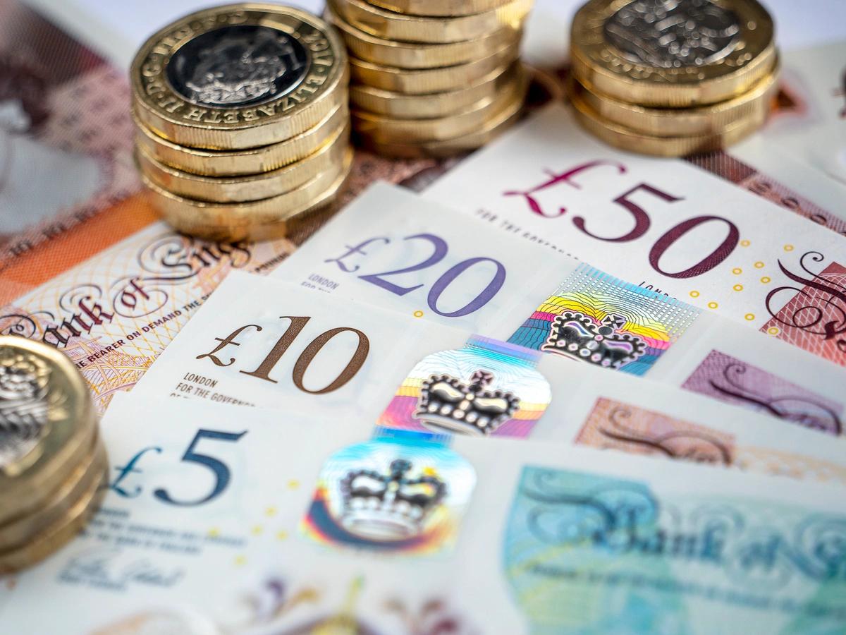 Piles of pound coins stacked up next to an array of notes