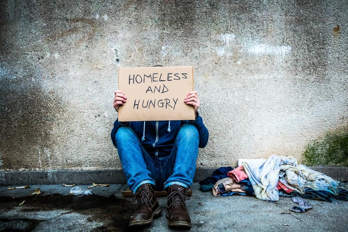 A homeless man with a 'homeless and hungry' sign