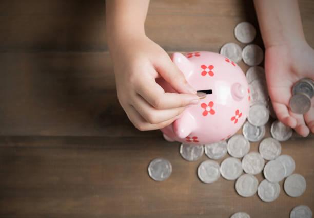 Image of a piggy bank with a child's hands putting coins in