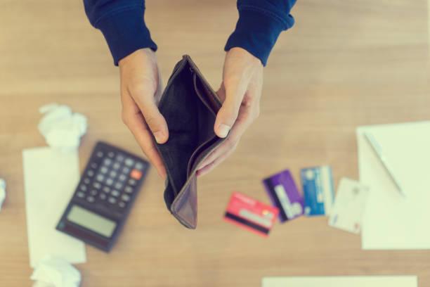 Image of a man opening an empty wallet in front of credit cards and a calculator. What to do if you can't afford to pay bills