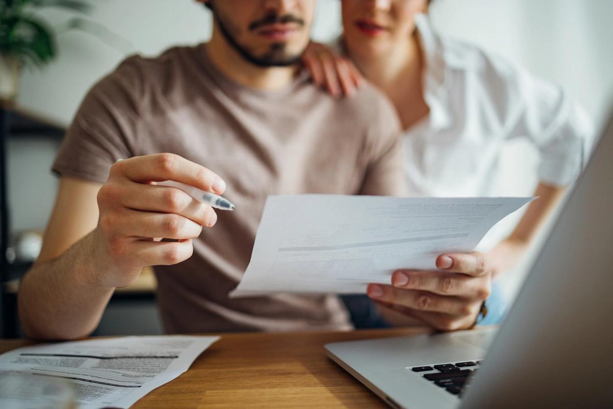 Close up of a couple going through their bills in front of a laptop