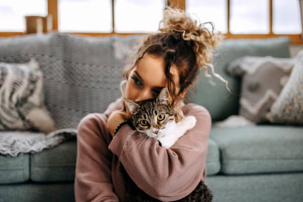 Image of a woman cuddling a cat in front of her sofa