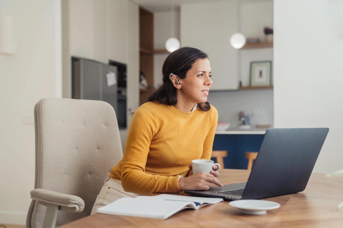 A woman with a hearing impairment using a laptop at home