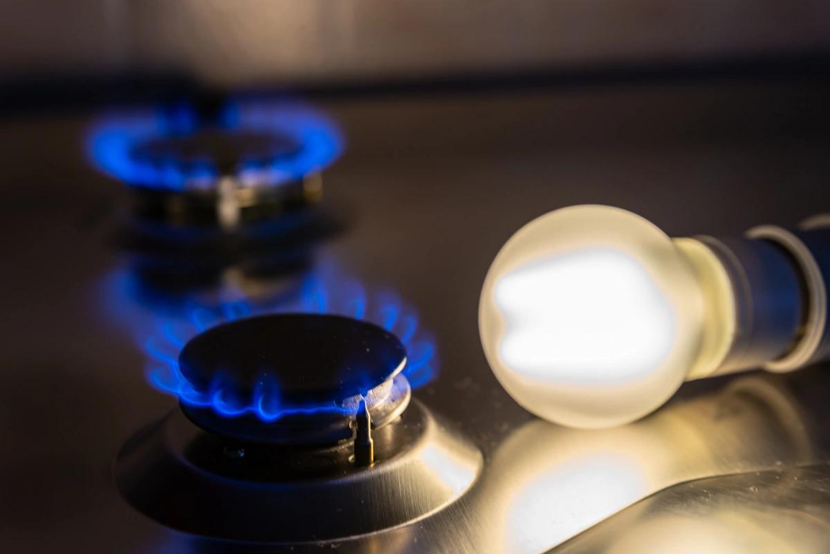 Two gas hob rings alight next to an illuminated light bulb