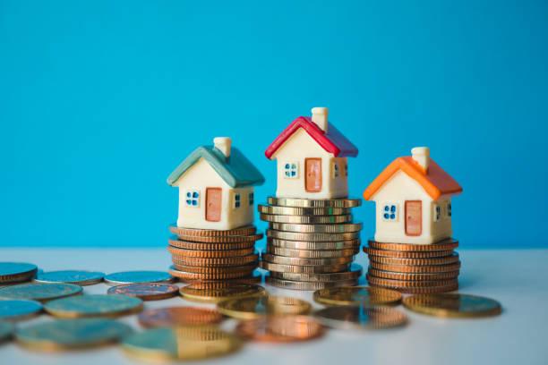 Illustrated image of three houses sitting on top of piles of coins