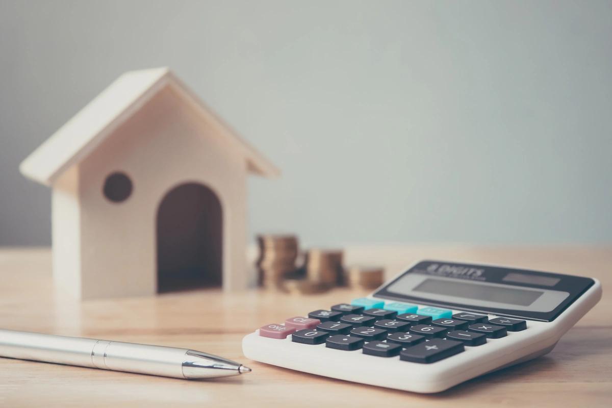 calculator next to model house and coins