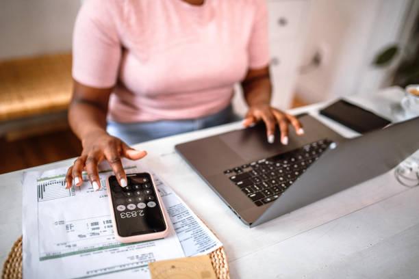 Image of someone working out a budget on a calculator and laptop. How to beat money FOMO .....  even if you're in debt or struggling