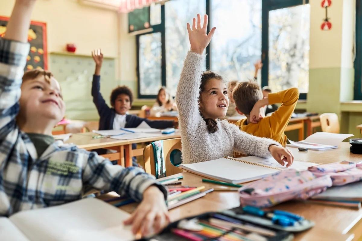 Primary school children raise their hands to answer a question in class