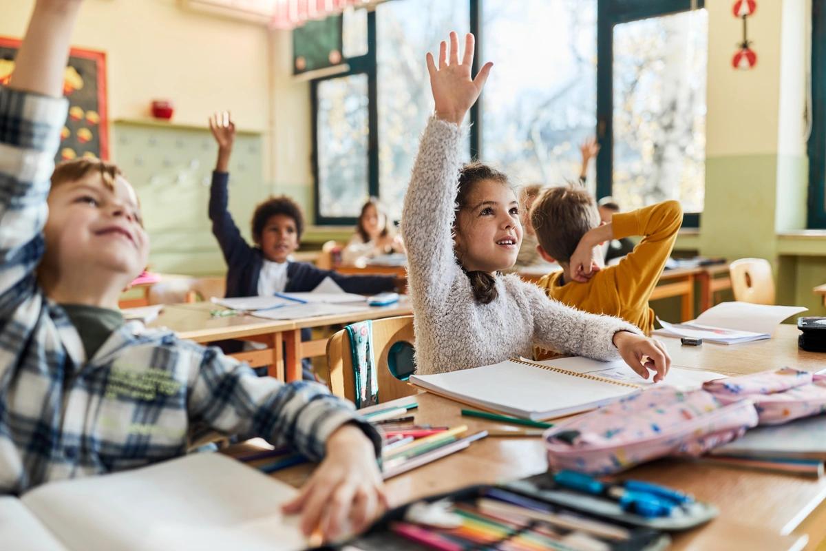 Children putting their hands up to an answer a question in class