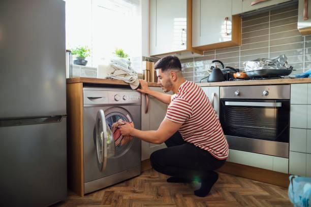 Image of a man loading a washing machine. 12 ways you're using white goods wrong and how it could be costing you £500 a year
