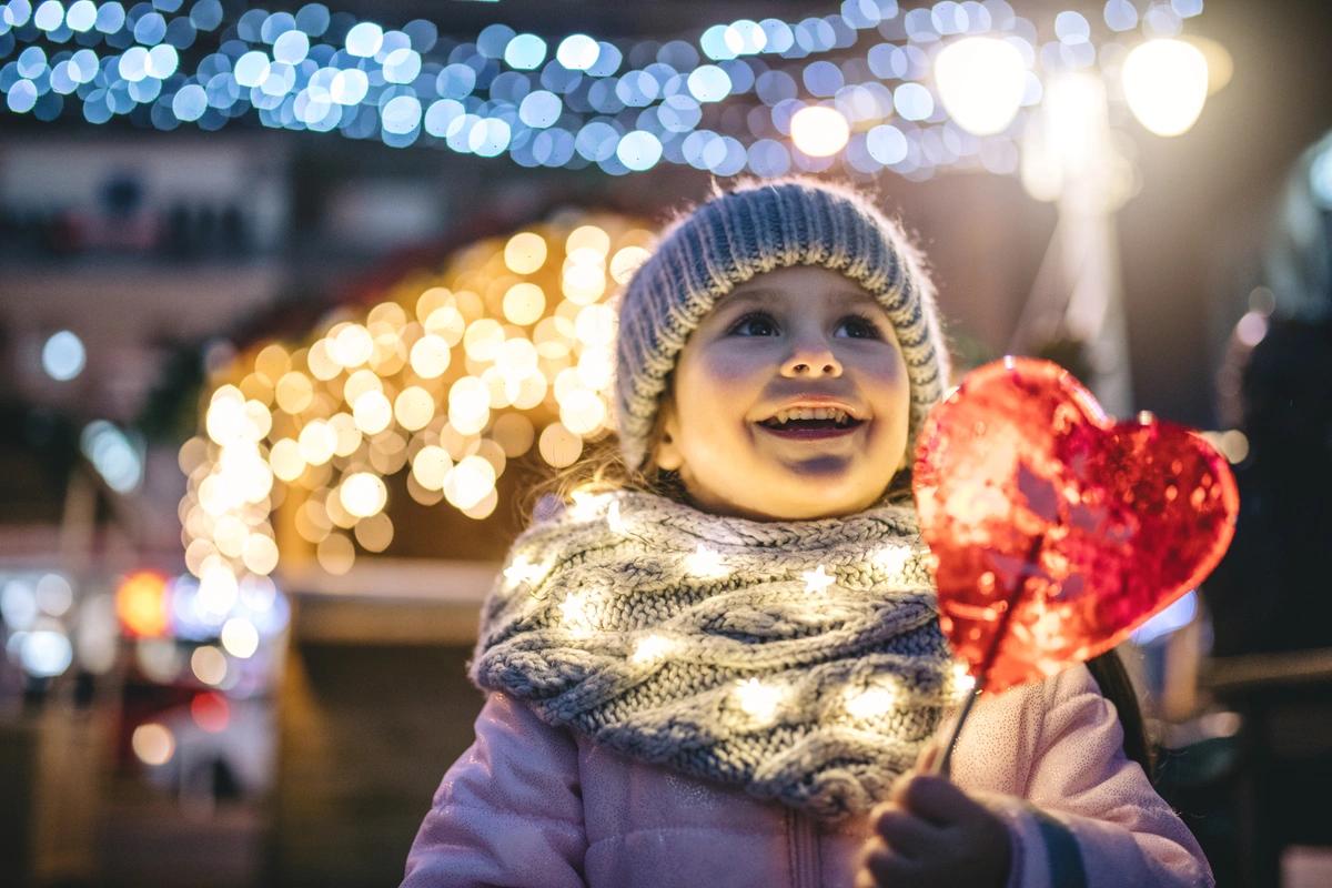 A smiling child wrapped up warm at an outdoor Christmas event