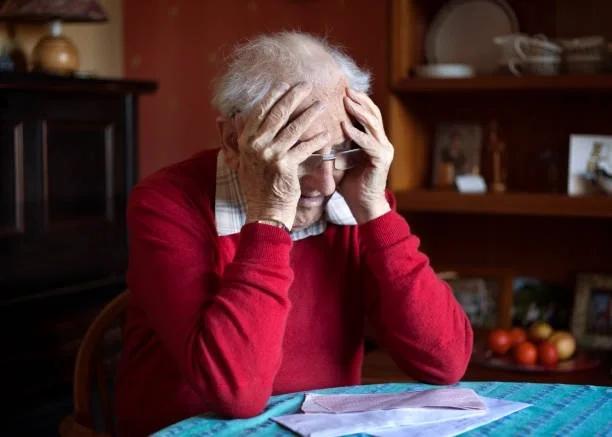 Image of a pensioner looking worried at bills. Why the triple lock is essential for low-income households.The state pension will rise more slowly from 2030, and the pensioners with the least will feel it first.
