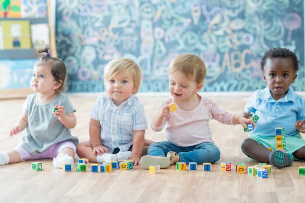 Image of babies sat in a row playing with building blocks