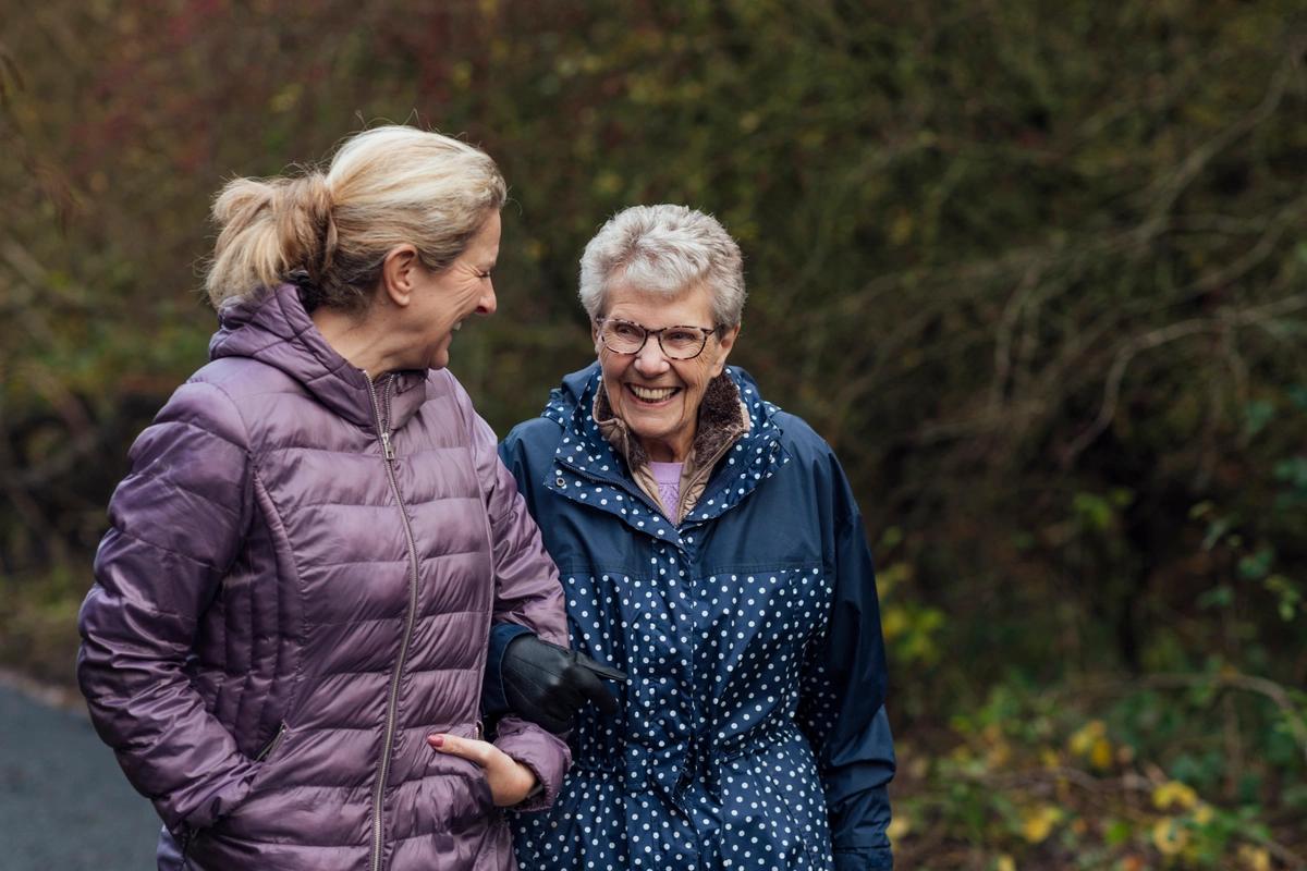 A grown-up daughter going for a walk with her mum who she cares for