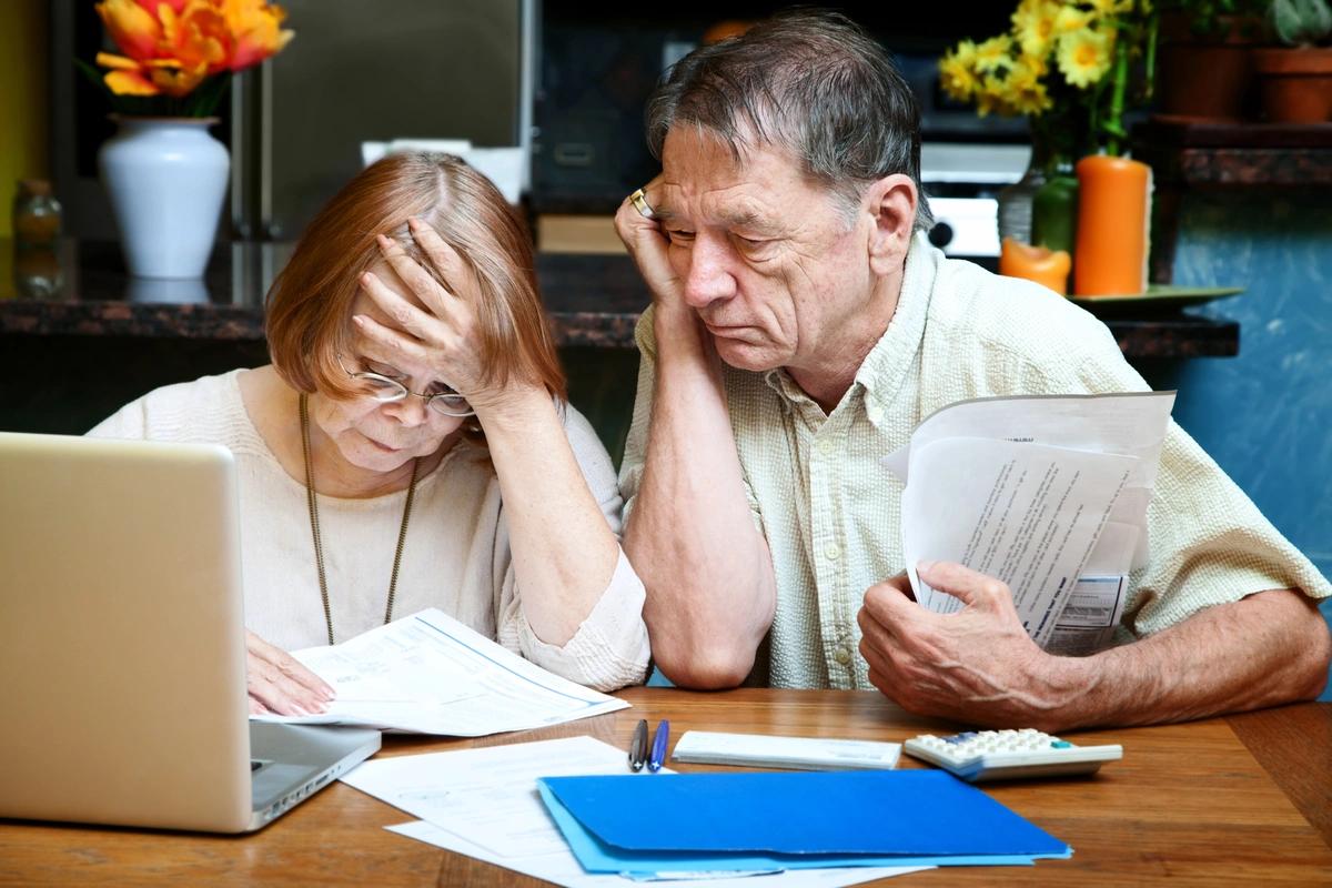 A retired, worried-looking couple go through their finances