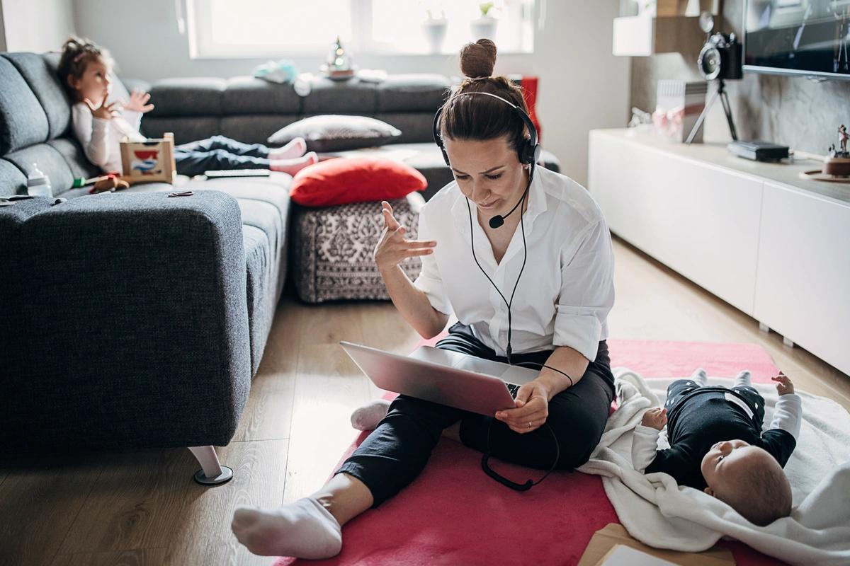 A working mum participates in an online meeting while looking after two children