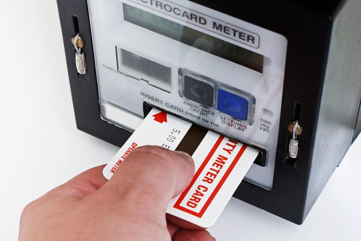Close-up of a hand inserting a card into an energy prepayment meter
