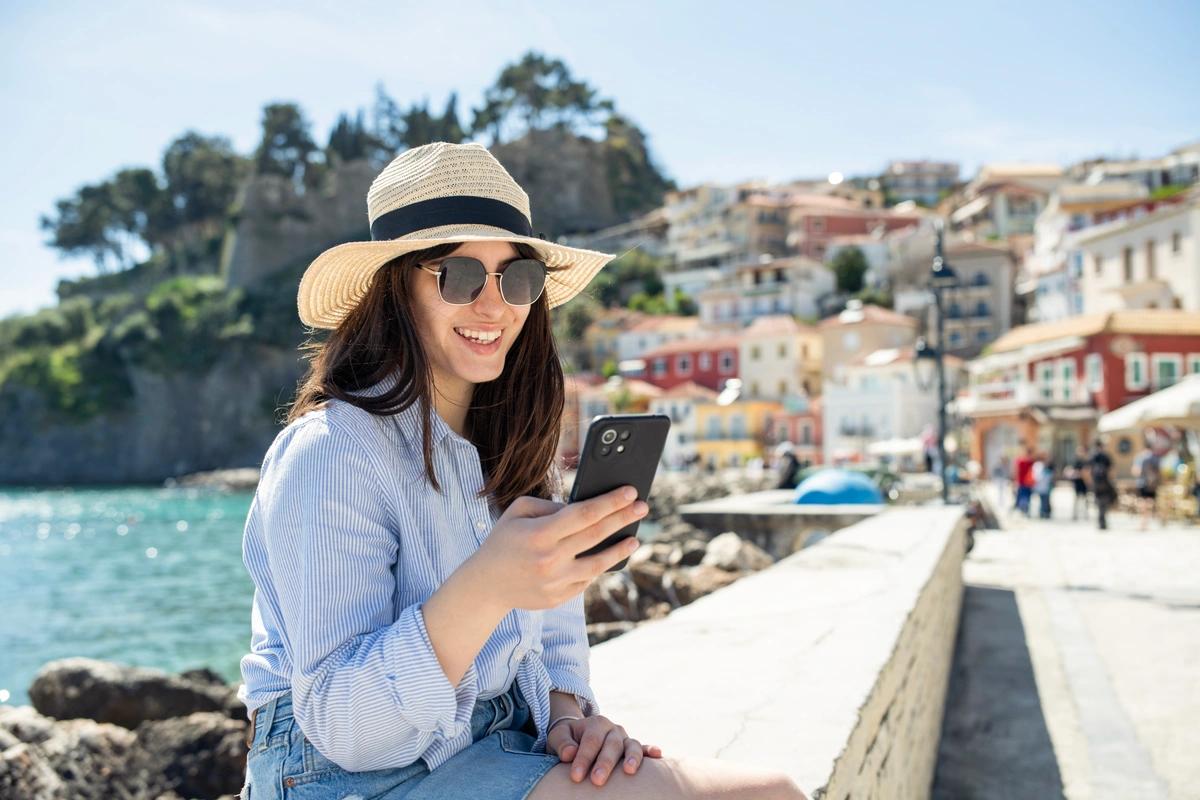 A woman sending a text while sitting in the sun on her summer holiday