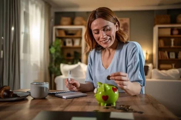 Image of someone putting money into a piggy bank. Simple swaps, clever checks and small hustles to boost your cash. Simple swaps, clever checks and small hustles to boost your bank balance
