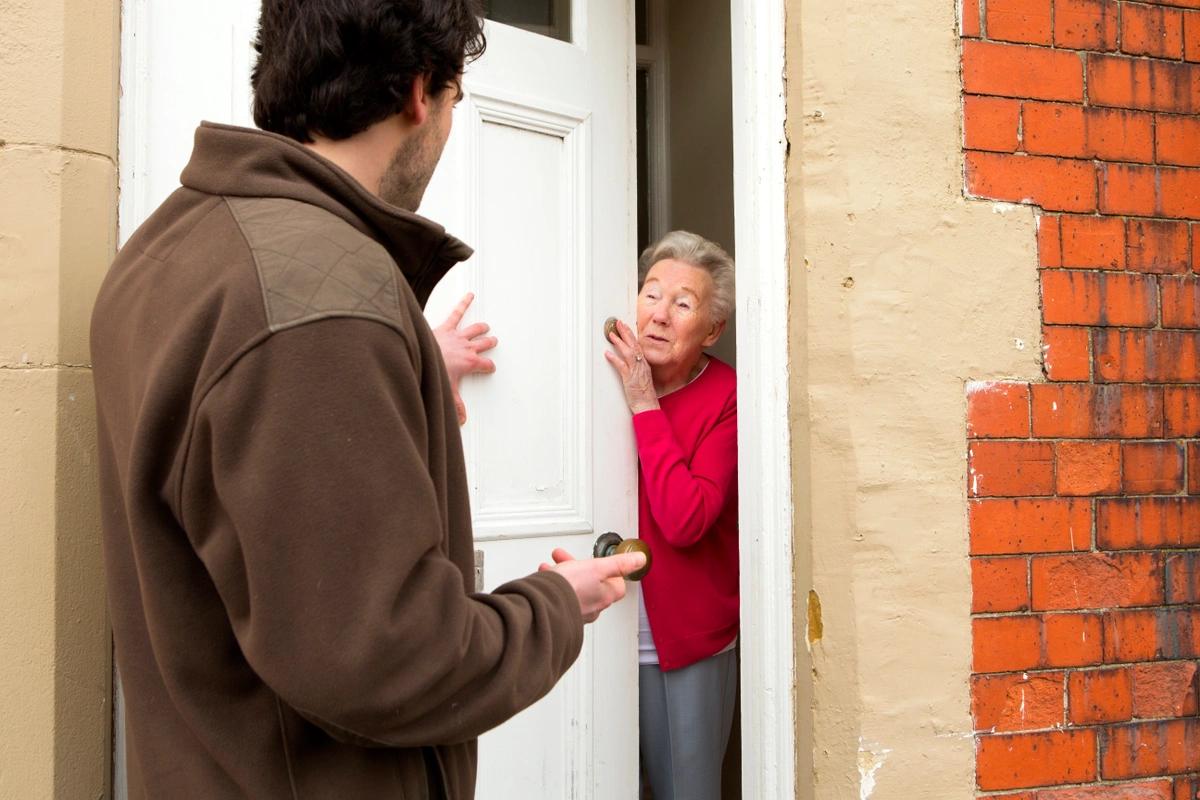 An elderly woman opens her door to a loan shark