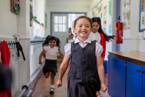 Picture of primary school children running down the school corridor smiling