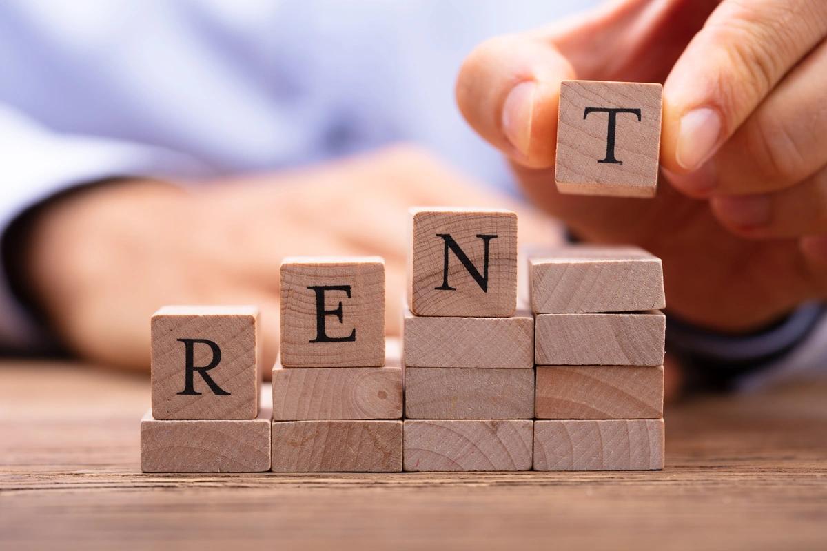 The word 'rent' spelt out in wooden blocks with each letter getting gradually higher