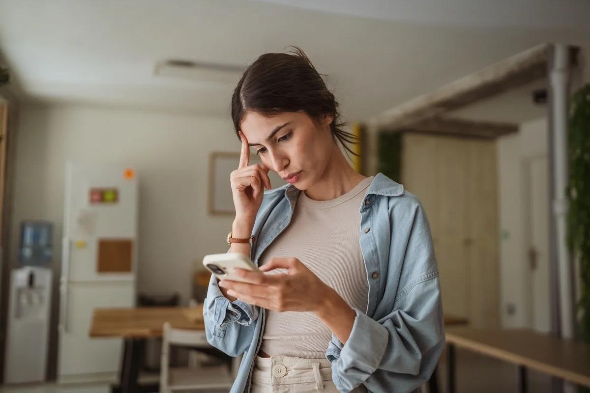 A confused woman looks at her energy bill on her phone
