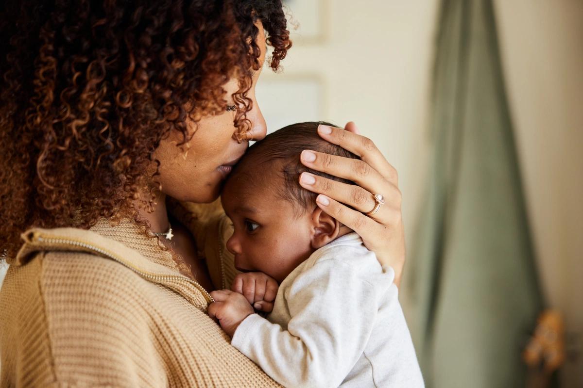 Head shot of a mum kissing the top of her baby's head