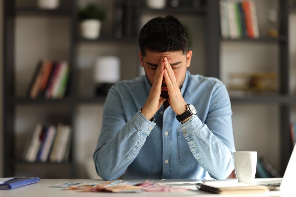 A man sitting at a desk with his head in his hands