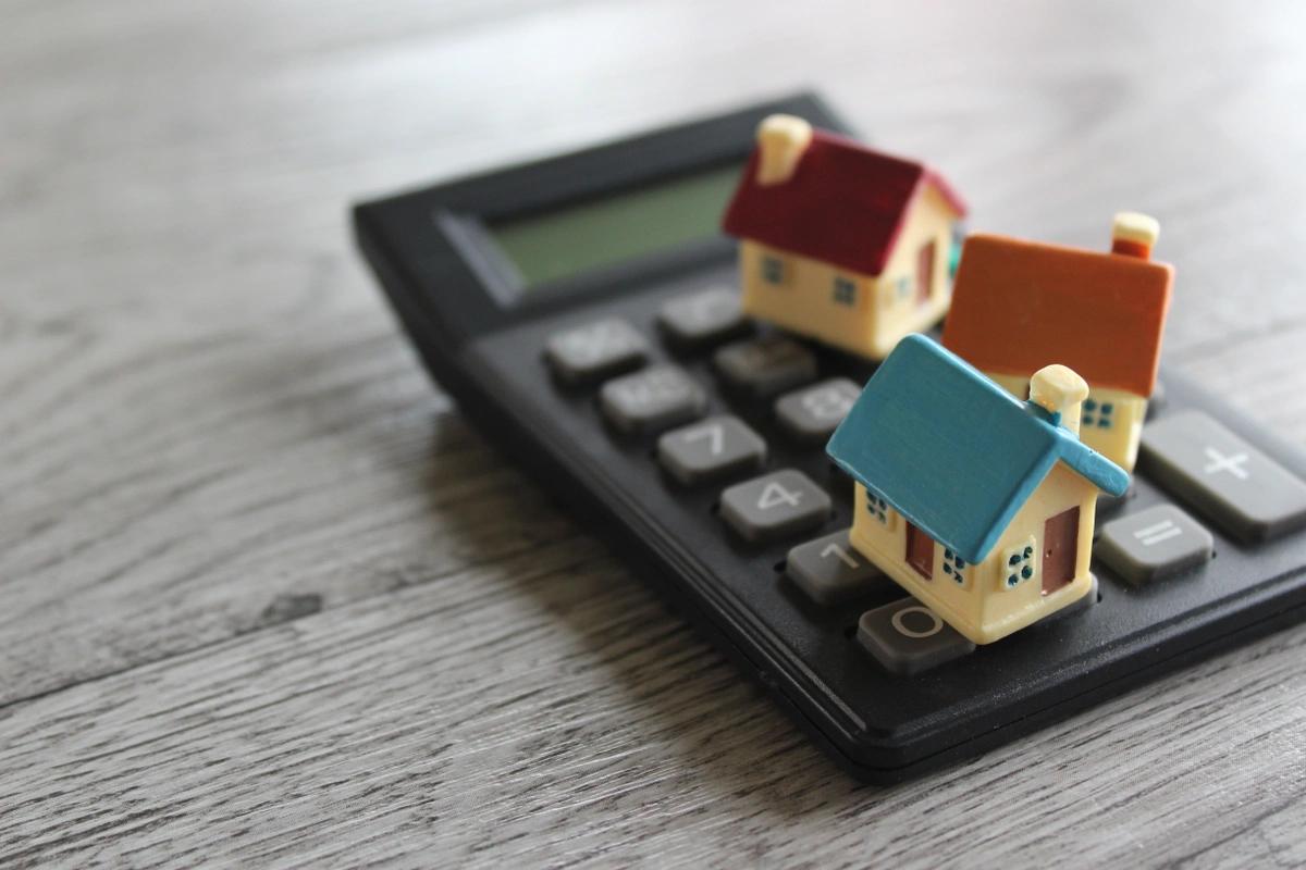 Three plastic model houses on a calculator