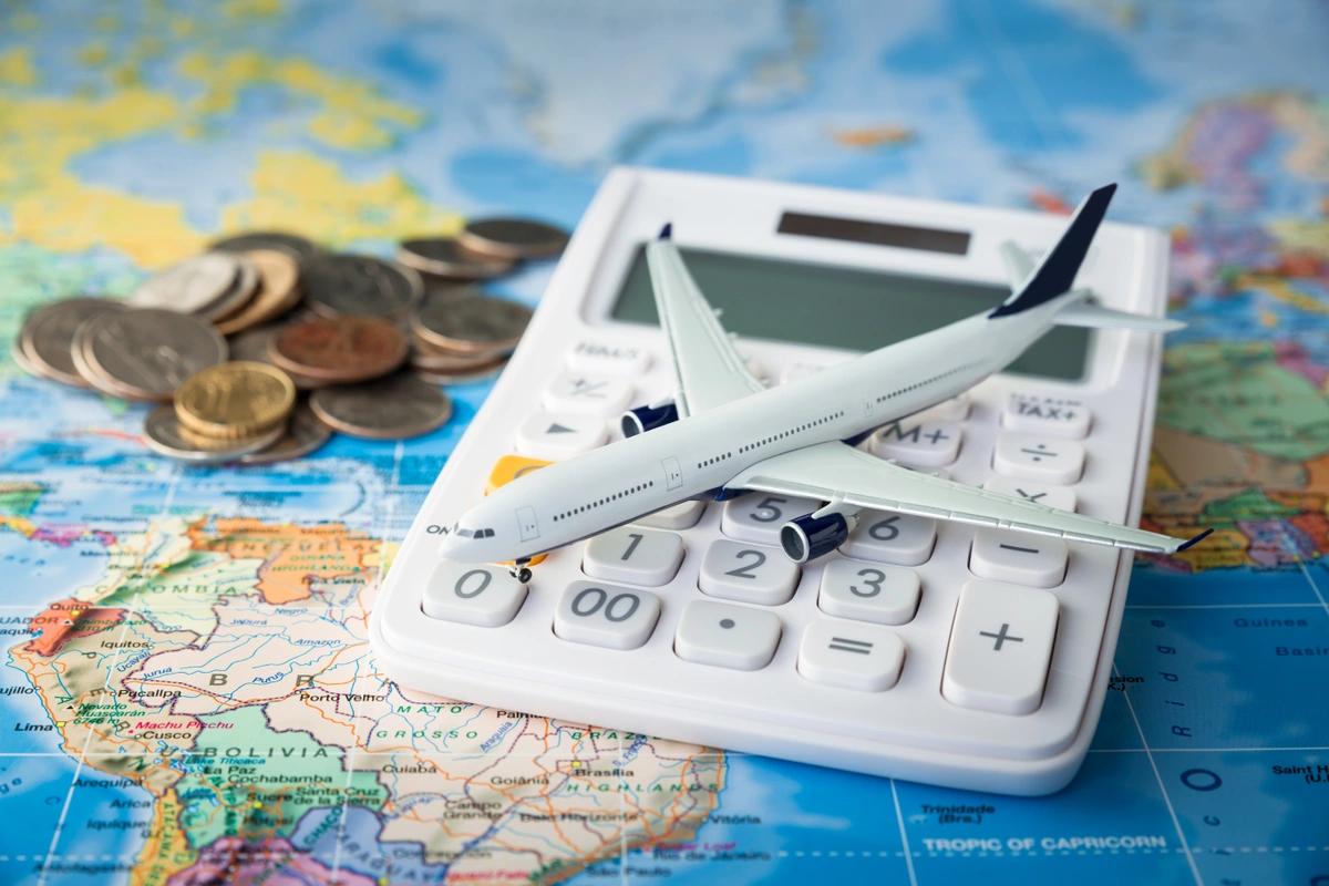A calculator, toy plane and some coins on top of a map of the world