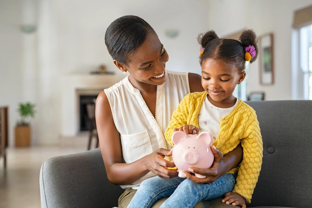 A mum uses a piggy bank to teach her daughter about money