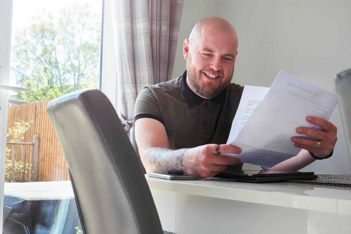 A smiling man reads his energy bill