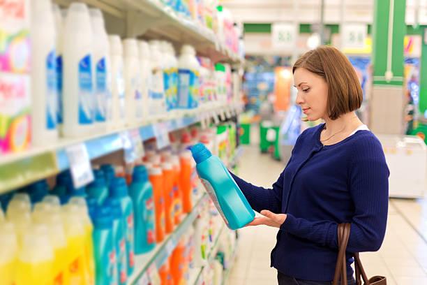 Image of a woman looking at a shelf of cleaning products. Thousands of everyday essentials to be slashed in price. Smarter Regulation